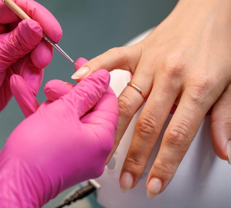 beautician applying Polish nails to woman nails. manicure process