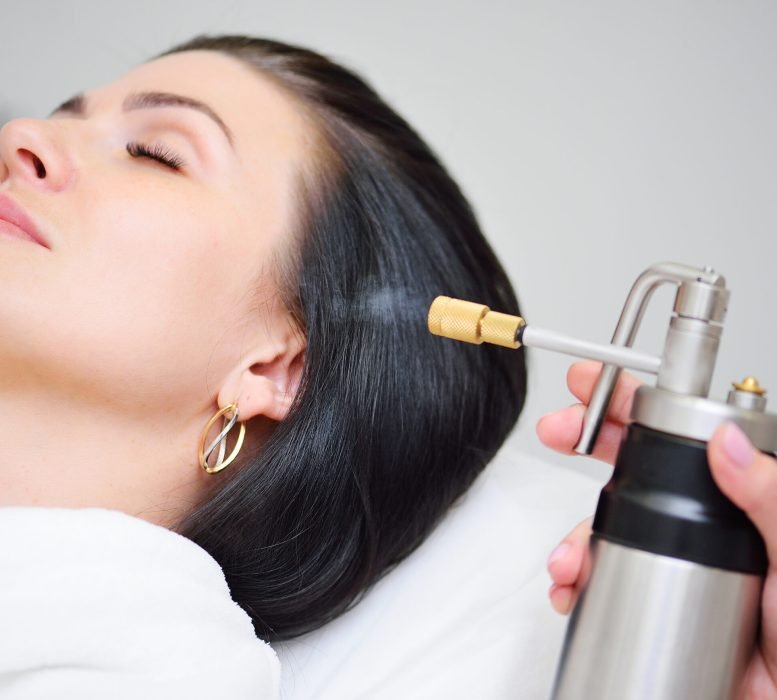 The cosmetologist makes a cryomassage of the face to the patient a cosmetological procedure of exposure to the skin with liquefied nitrogen using a cryodestructor apparatus