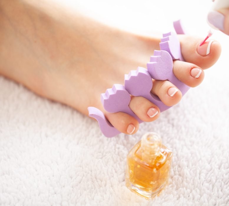 Hand and Nail Care. Beautiful Women's Feet with Pedicure in Beauty Salon. The Master Applying on Nail. Spa Manicure.