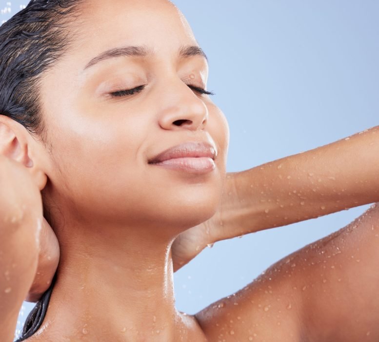 Nothings better than this. Shot of a young woman taking a shower against a blue background